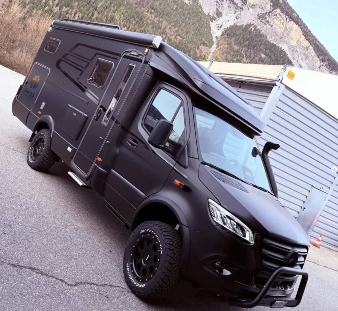 Mattschwarzes Offroad-Reisemobil mit Geländefahrwerk in den Bergen